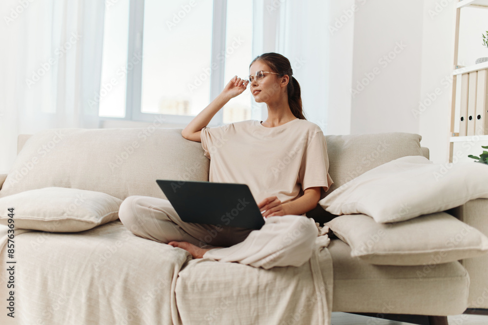 Smiling woman working on laptop in cozy living room Smiling woman working on laptop in cozy living room