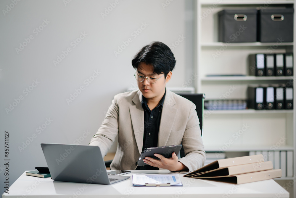 Young businessman working with working notepad, tablet and laptop documents talking on the smartphone, tablet and laptop Young businessman working with working notepad, tablet and laptop documents talking on the smartphone, tablet and laptop