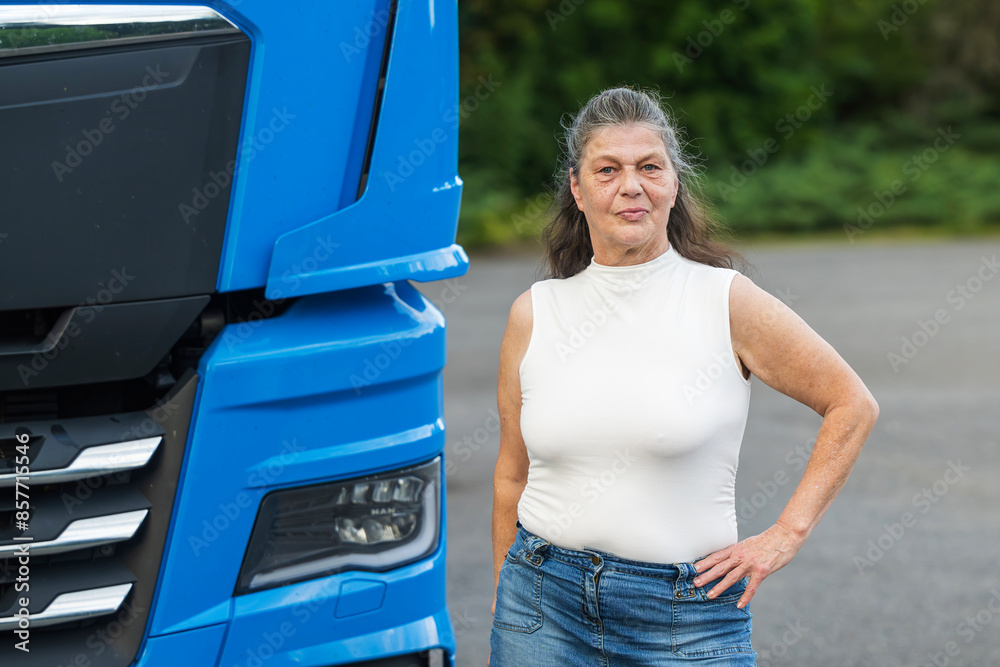 Attraktive ältere LKW Fahrerin steht neben ihrem LKW