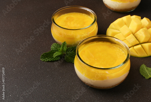 Cheesecake with mango in a glass on a brown background photo