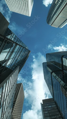 Low angle view of city skyline buildings, blue sky and glass mirrored facades.	