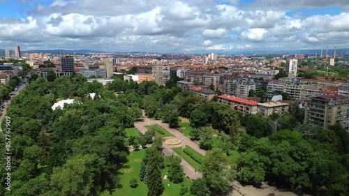 Aerial shot of Zaimov Park in Sofia, Bulgaria. Establishing shot of a green park in an East European capital city on a summer day with a beautiful sky with fluffy white clouds. photo