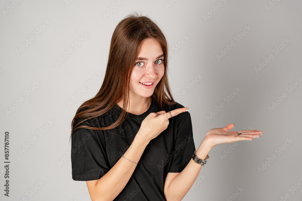 Smiling Young Woman Pointing to Copy Space Against a Grey Background