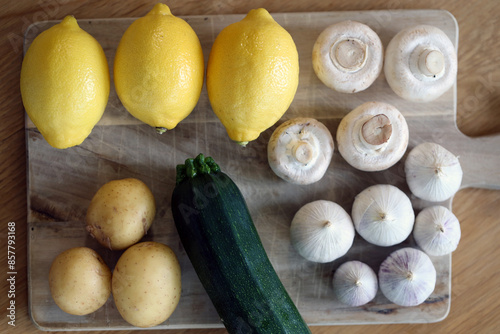 Scandinavian summer, fall season cuisine. Ingredients for a healthy meal: potatoes, garlic, zucchini and lemons on a wooden rustic cutting board. Fresh raw vegetables from season's harvest. Closeup.