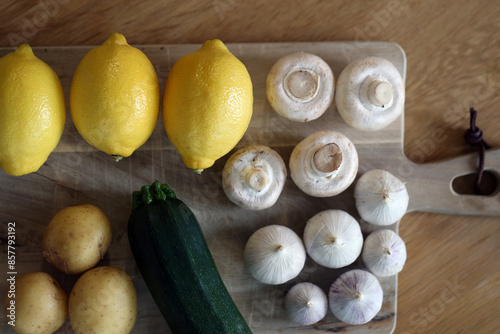 Scandinavian summer, fall season cuisine. Ingredients for a healthy meal: potatoes, garlic, zucchini and lemons on a wooden rustic cutting board. Fresh raw vegetables from season's harvest. Closeup.