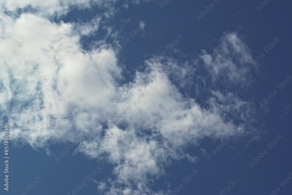 white cloud against a blue sky, illuminated by the sun from one side