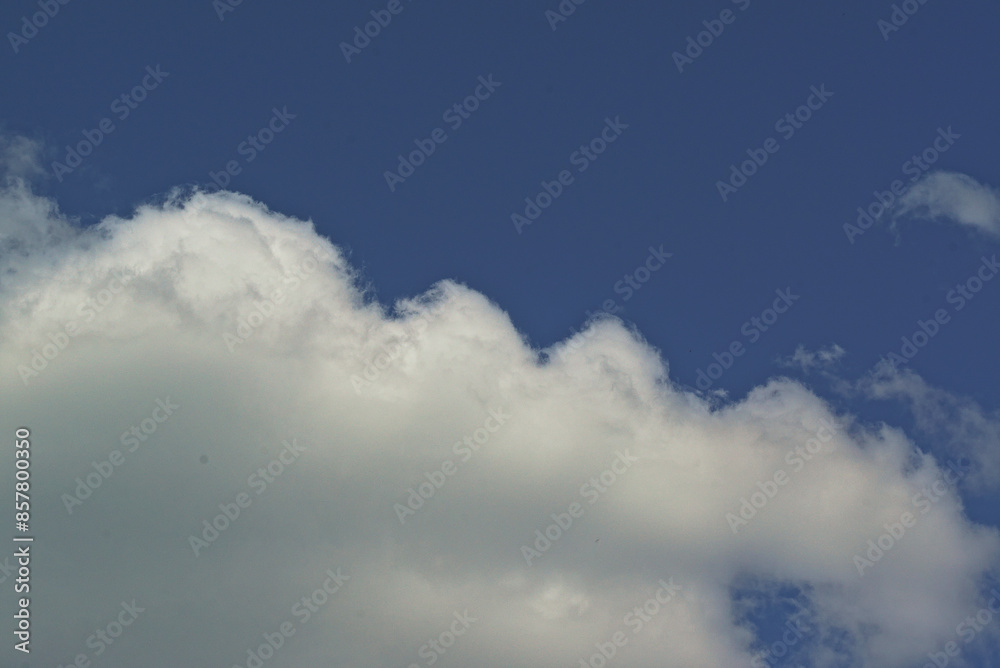 Obraz premium white cloud against a blue sky, illuminated by the sun from one side