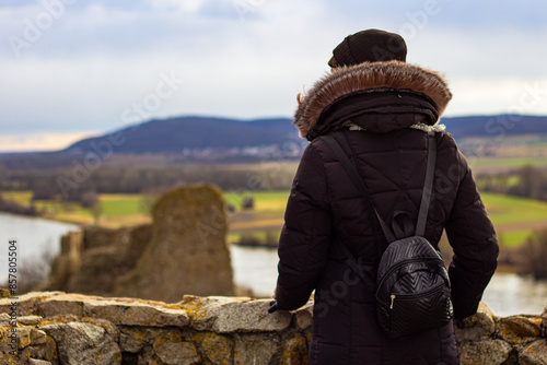 Photography Woman tourist in black coat with black backpack at the top of Devin castle (Slovak: Devinsky hrad)