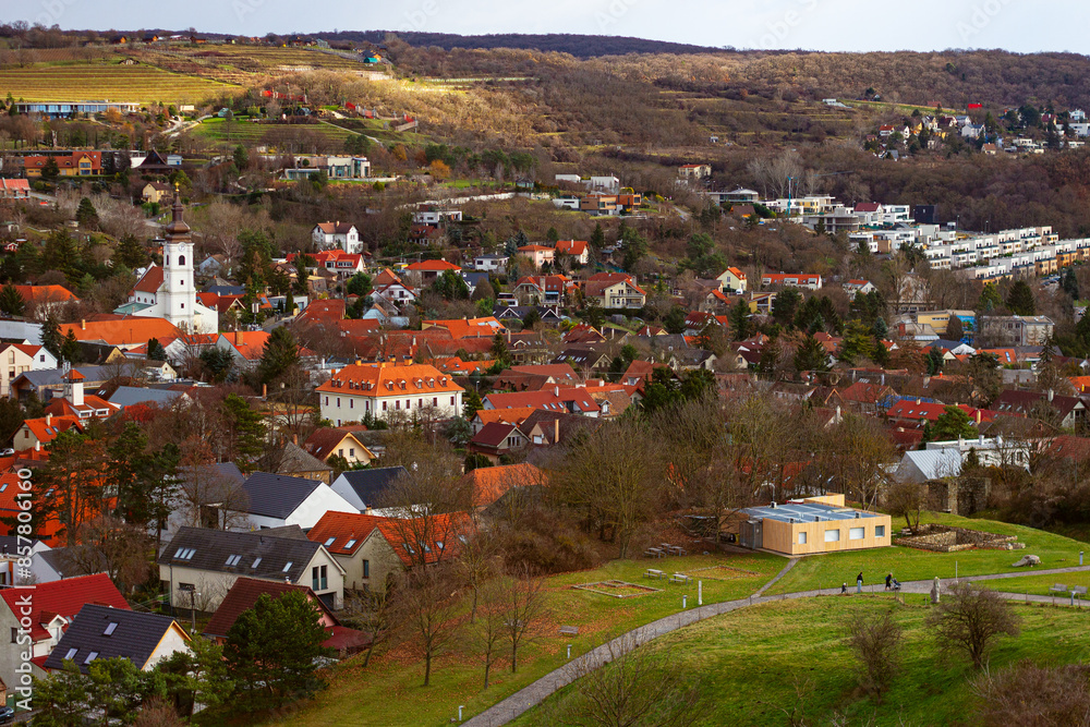 Fototapeta premium Devín district with cozy buildings with red tiles and Parish Church of the Holy Cross towering over the city. It is an important archaeological site situated near the ruins of Devín Castle