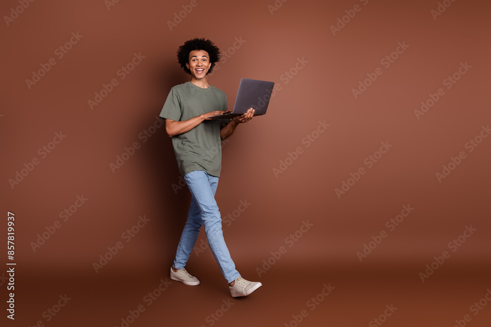 Photo portrait of young guy in gray t shirt strolling and holding laptop apple macbook air m3 processor isolated on brown color background Photo portrait of young guy in gray t shirt strolling and holding laptop apple macbook air m3 processor isolated on brown color background