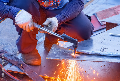 фотографія Cropped image of welder is cutting iron plate with acetylene gas welding torch m