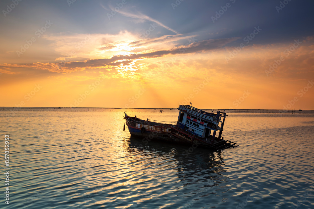 A fishing boat is broken or abandoned in the middle of the sea at sunset in Chonburi, Thailand. A fishing boat is broken or abandoned in the middle of the sea at sunset in Chonburi, Thailand.