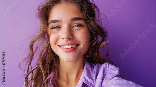 Smiling young girl taking a selfie with a peace sign in a purple shirt