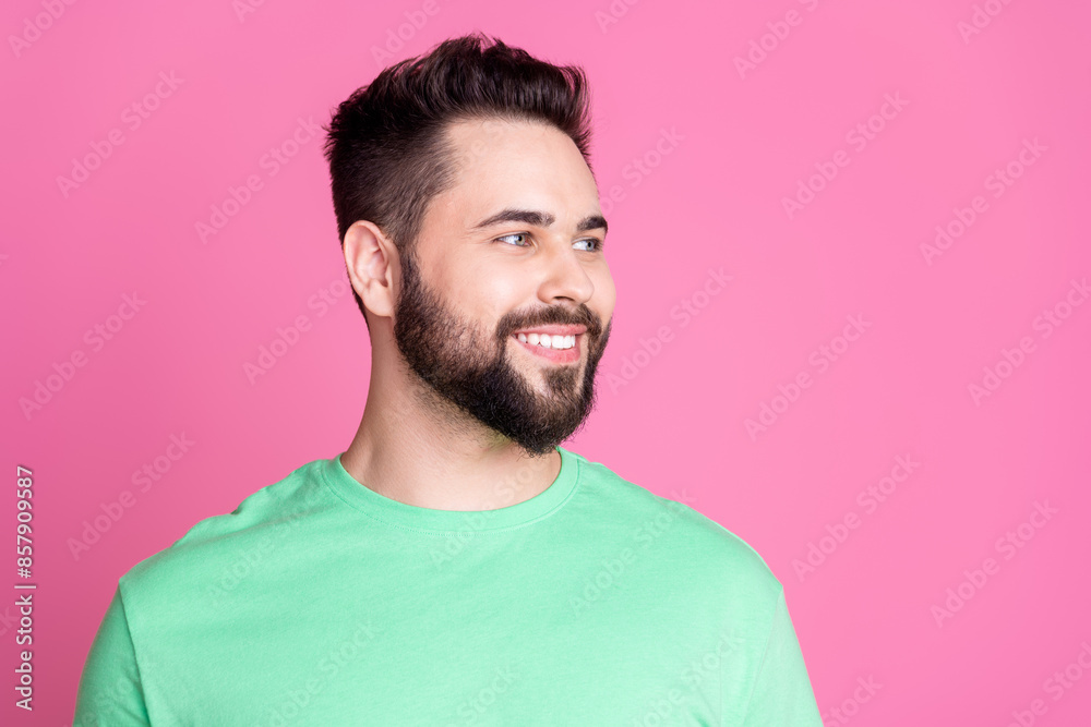 Obraz premium Photo of positive cheerful guy with stylish beard dressed green t-shirt look at discount empty space isolated on pink color background