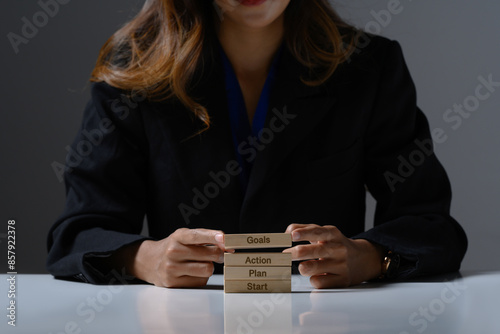 Businesswoman holding wooden blocks with words goal, action, plan and start. Business motivational concept