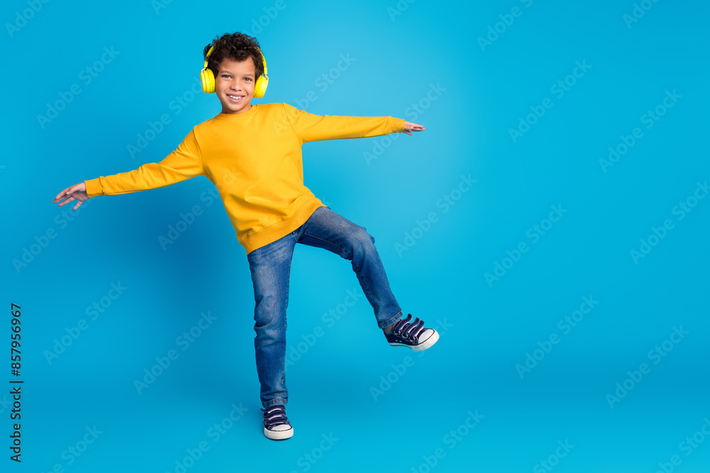 Full body photo of cute little boy headphones dancing dressed stylish yellow clothes isolated on blue color background Full body photo of cute little boy headphones dancing dressed stylish yellow clothes isolated on blue color background