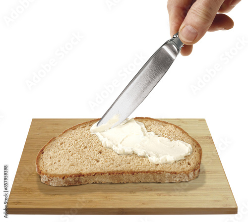 Brotscheibe auf Holzbrettchen wird mit Butter bestrichen von Hand mit Messer photo