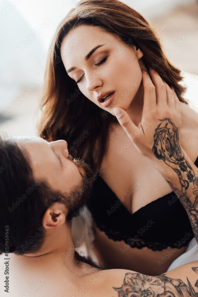 Naklejka premium Beautiful passionate couple is having sex on bed. Woman wearing sexy lace lingerie