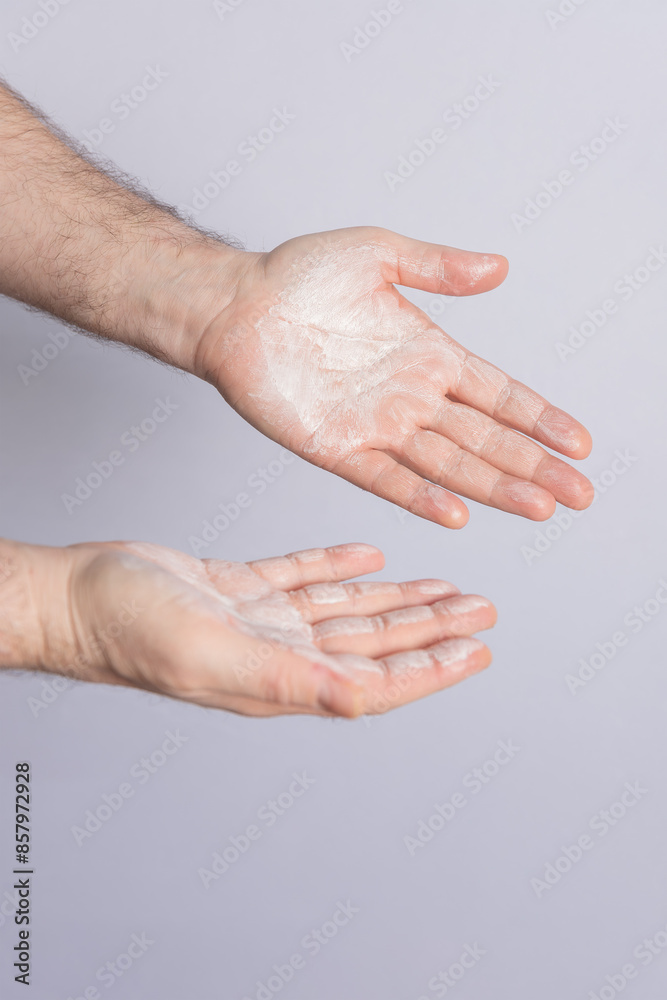 Fototapeta premium Male hands with palms up filled with cosmetic product isolated on grey background. Copy space. Concept of cosmetics, male care and hair care
