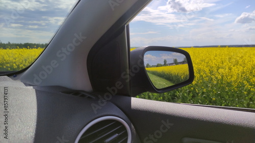 Obraz na płótnie View of a car mirror on Beautiful green field and blue sky. Car travel ecological tourism w salonie