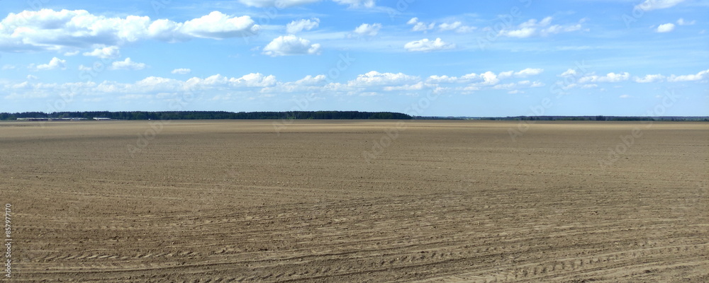Brown field soil and blue sky with clouds panorama