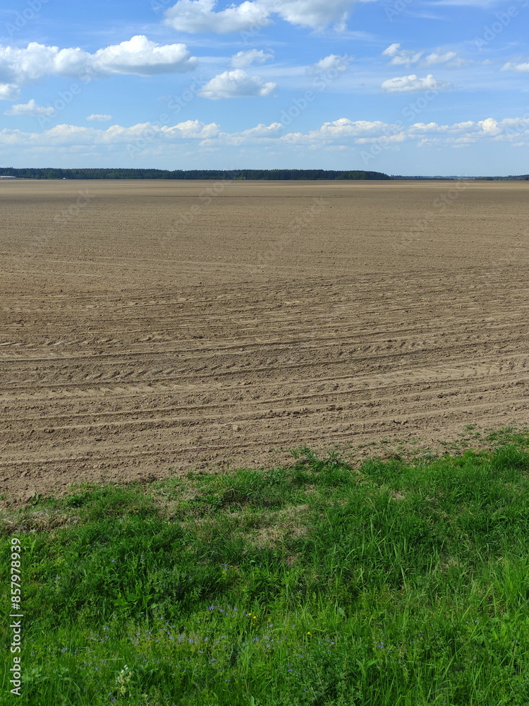 Cultivated plowed brown field at spring day. European environment landscape