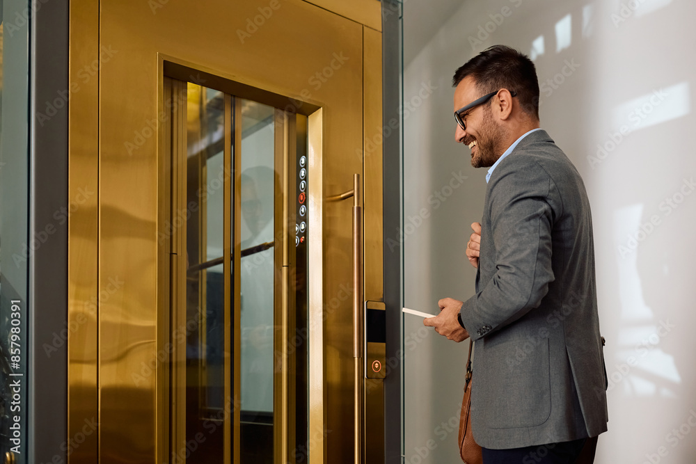 Happy businessman waiting for elevator button in office hallway Happy businessman waiting for elevator button in office hallway