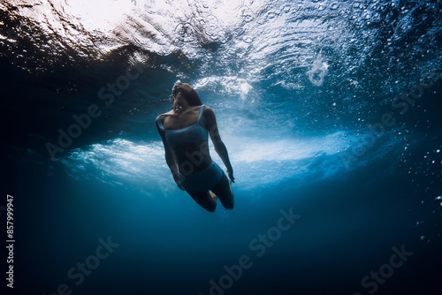 Woman swims underwater with crashing wave in ocean photo