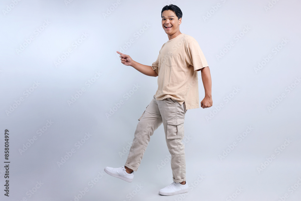 Full Length Of Young Asian Man Walking And Pointing To Aside For Free Space Isolated On White Background Full Length Of Young Asian Man Walking And Pointing To Aside For Free Space Isolated On White Background
