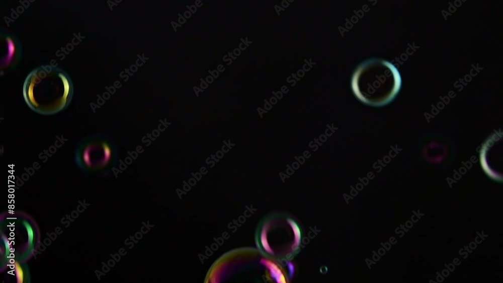 Soap bubble background. Colorful soap bubbles fly across black background. slow motion