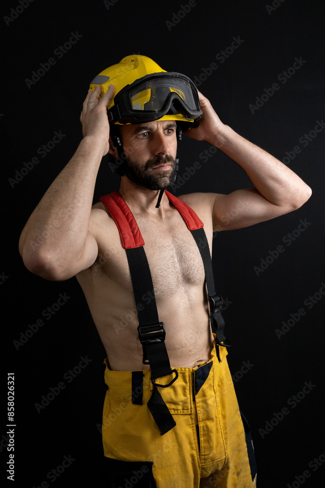 Fototapeta premium Firefighter shirtless adjusting the helmet
