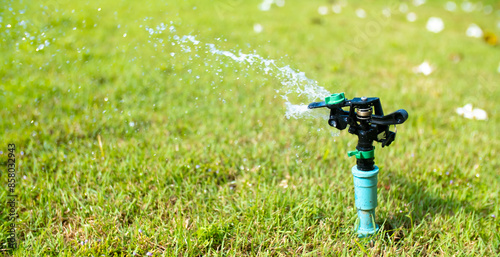 Sprinkler for automatic lawn watering. Lawn cultivation and care, garden irrigation devices. Rainbow over the garden on a sunny day.