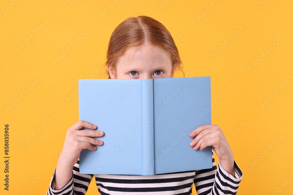 Cute little girl with book on yellow background Cute little girl with book on yellow background