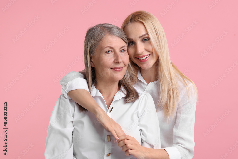 Family portrait of young woman and her mother on pink background Family portrait of young woman and her mother on pink background