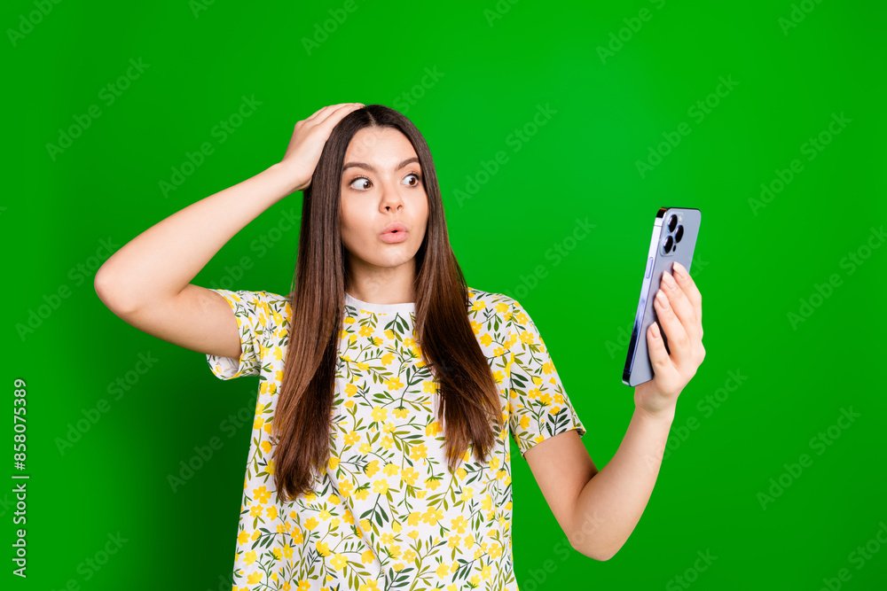 Naklejka premium Photo portrait of lovely teen lady hold device nervous amazed dressed stylish flowers print garment isolated on green color background