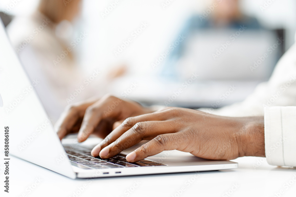 Manager typing on laptop keyboard in busy office, selective focus on hands Manager typing on laptop keyboard in busy office, selective focus on hands