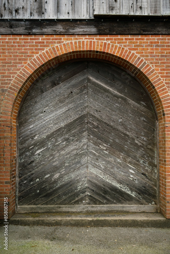 old brick wall with round barn wood door photo