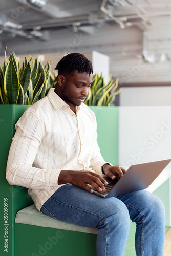 Serious African American, freelancer working on his laptop in a modern office space © Maria Vitkovska