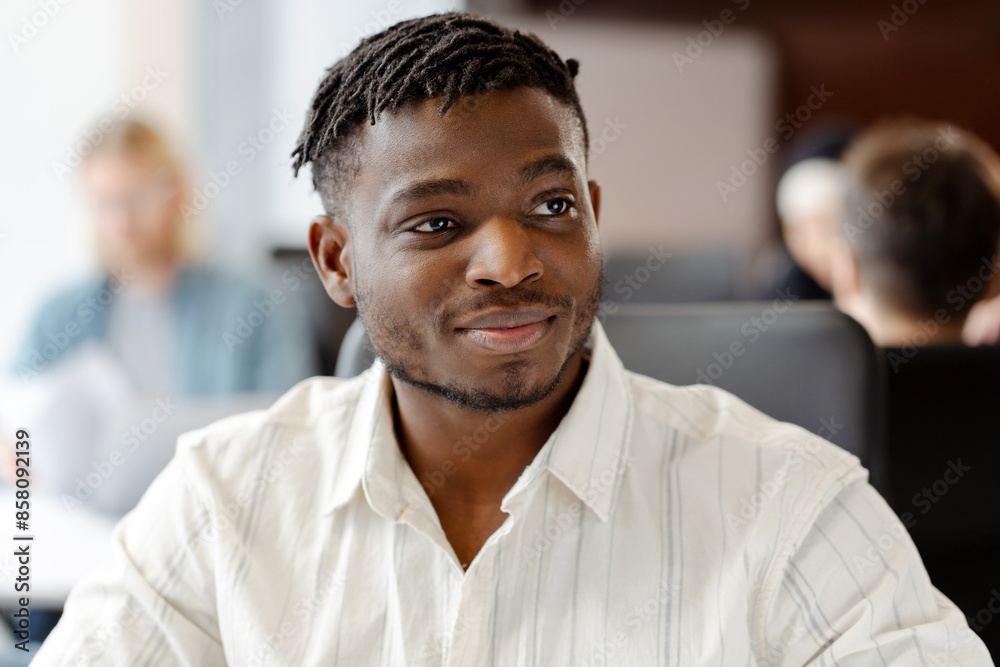 Young professional smiling while working in busy open plan office looking away Young professional smiling while working in busy open plan office looking away