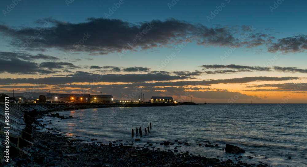 Long exposure blue hour image of shore sea wall & harbor with light starbursts