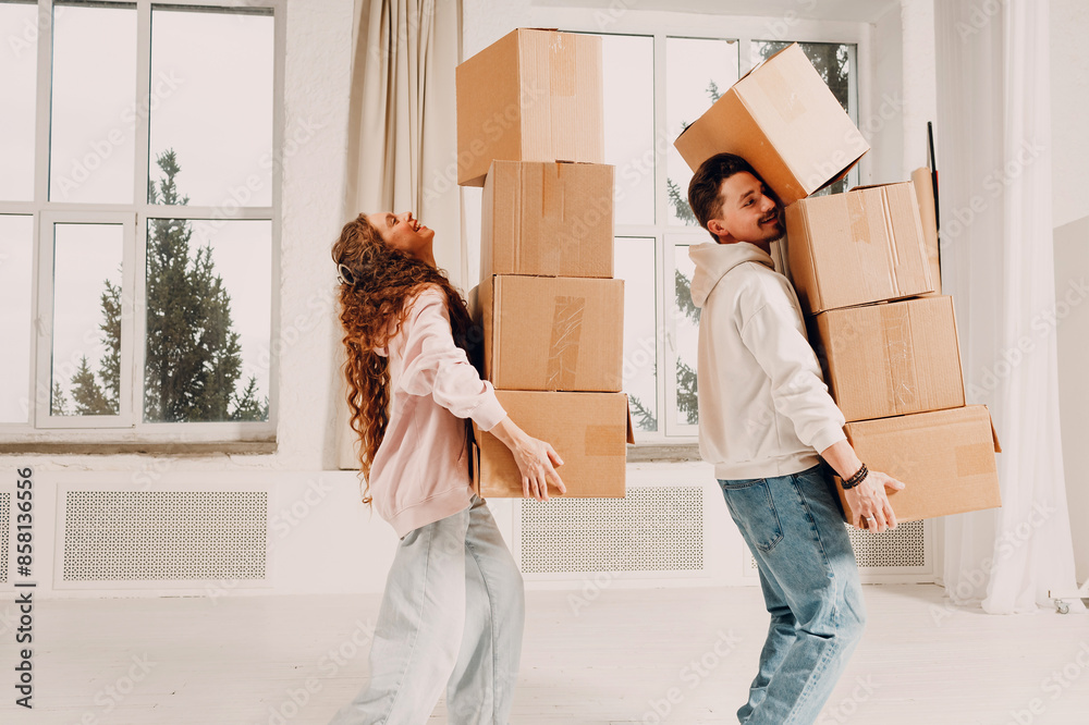 Happy young family couple man and woman moving with cardboard boxes to new estate home apartment.