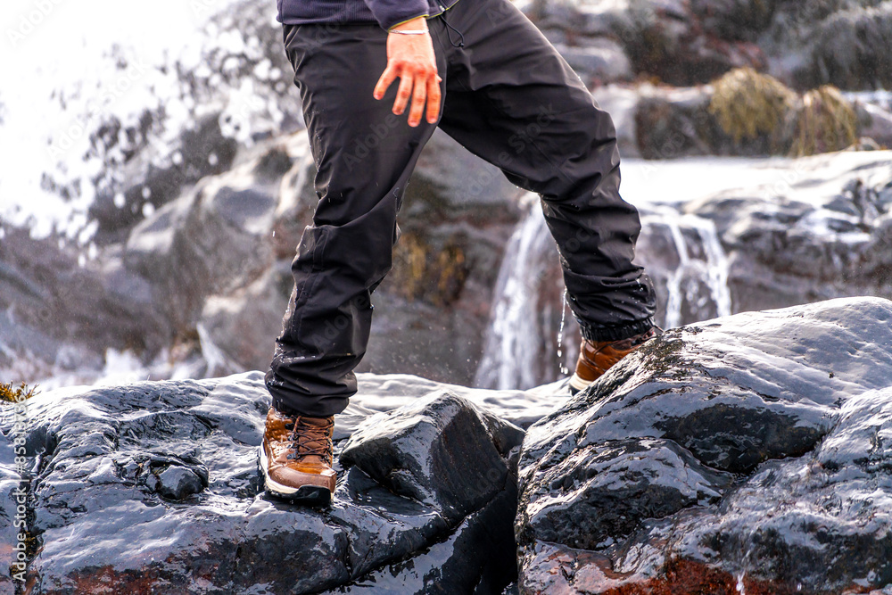 A person is standing on a rock with their feet in the water A person is standing on a rock with their feet in the water