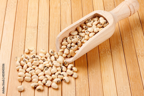 Raw dried black eyed peas bean in wooden ladle isolated on bamboo table