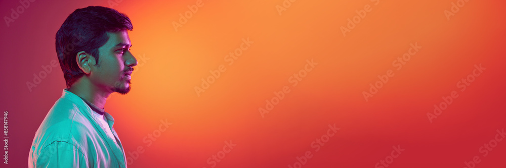 Banner. Side view portrait of young Indian man in looking at distance with confidence neon light against gradient studio background. Concept of fashion and style, human emotions, business. Copy space Banner. Side view portrait of young Indian man in looking at distance with confidence neon light against gradient studio background. Concept of fashion and style, human emotions, business. Copy space