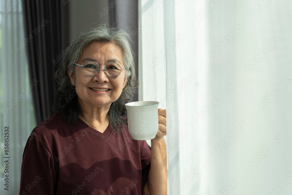 Mature Asian woman with cup of coffee  in living room at home