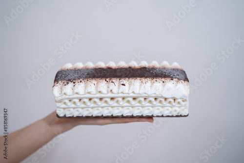 A rectangular piece of layered ice cream held in hand.