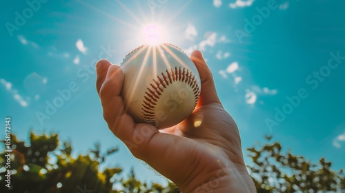 太陽の光を浴びた手に握られた野球ボール
