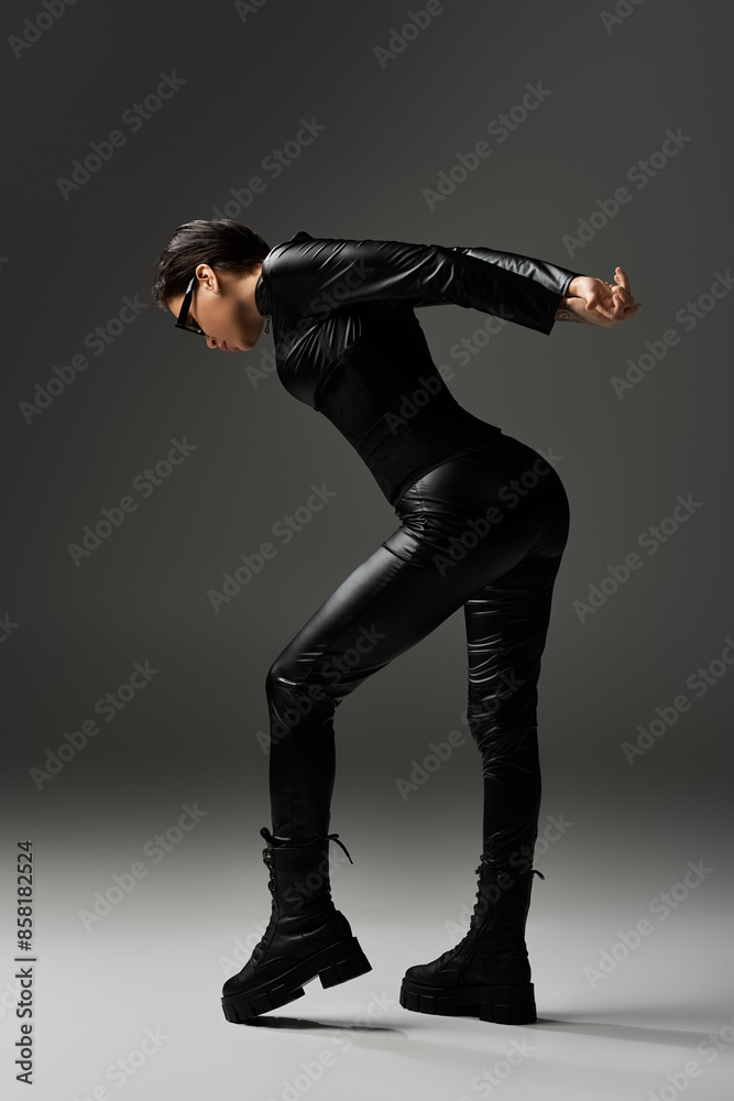 Woman in a black leather jumpsuit strikes a seductive pose, casting a long shadow. Woman in a black leather jumpsuit strikes a seductive pose, casting a long shadow.