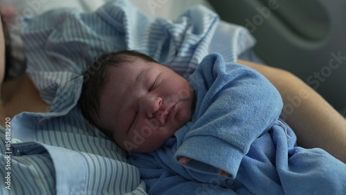 Serene newborn baby resting on mother's arm during first day of life, calm peaceful infant intial days at hosipital clinic after birth photo