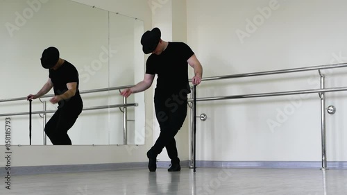Jazz dance or caberet rehearsal in the studio with a cane, a young guy in a gangster hat clicks his fingers. Creative dance blues man, in black clothes photo